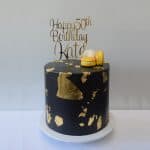 Custom wood cutouts, custom gold cake topper on black and gold cake says happy 50th birthday kate